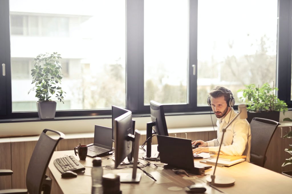 man at open plan office computer with headphones